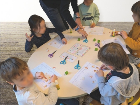 Des enfants de maternelles assis autour d'une table en train de faire une activité manuelle