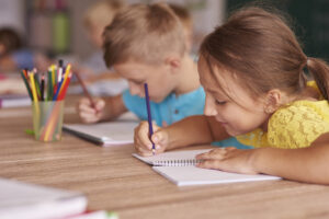 Deux enfants en train d'écrire sur un bureau